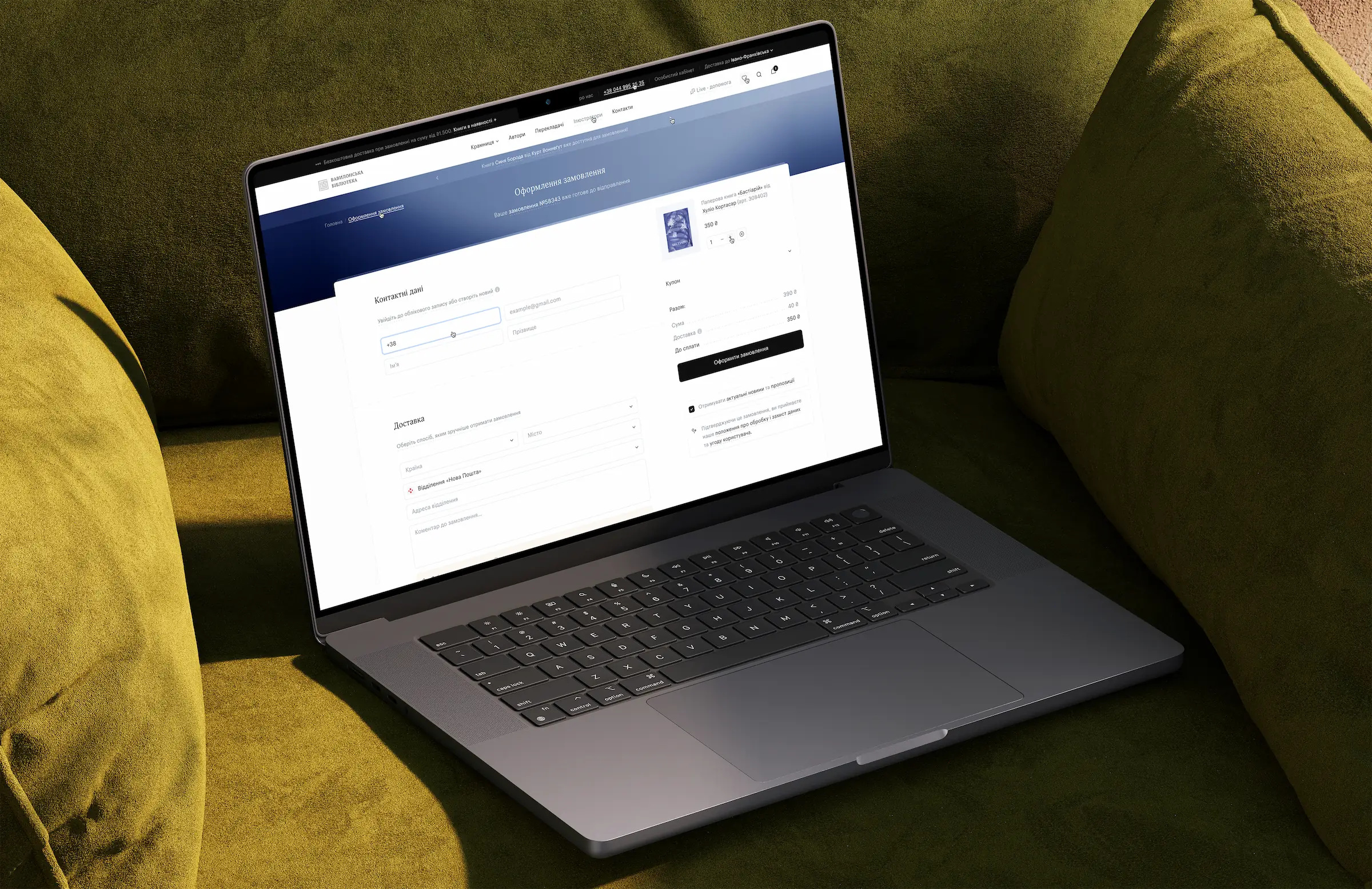 A laptop resting on a green sofa displays the checkout page of the Babylon Library online bookstore.
